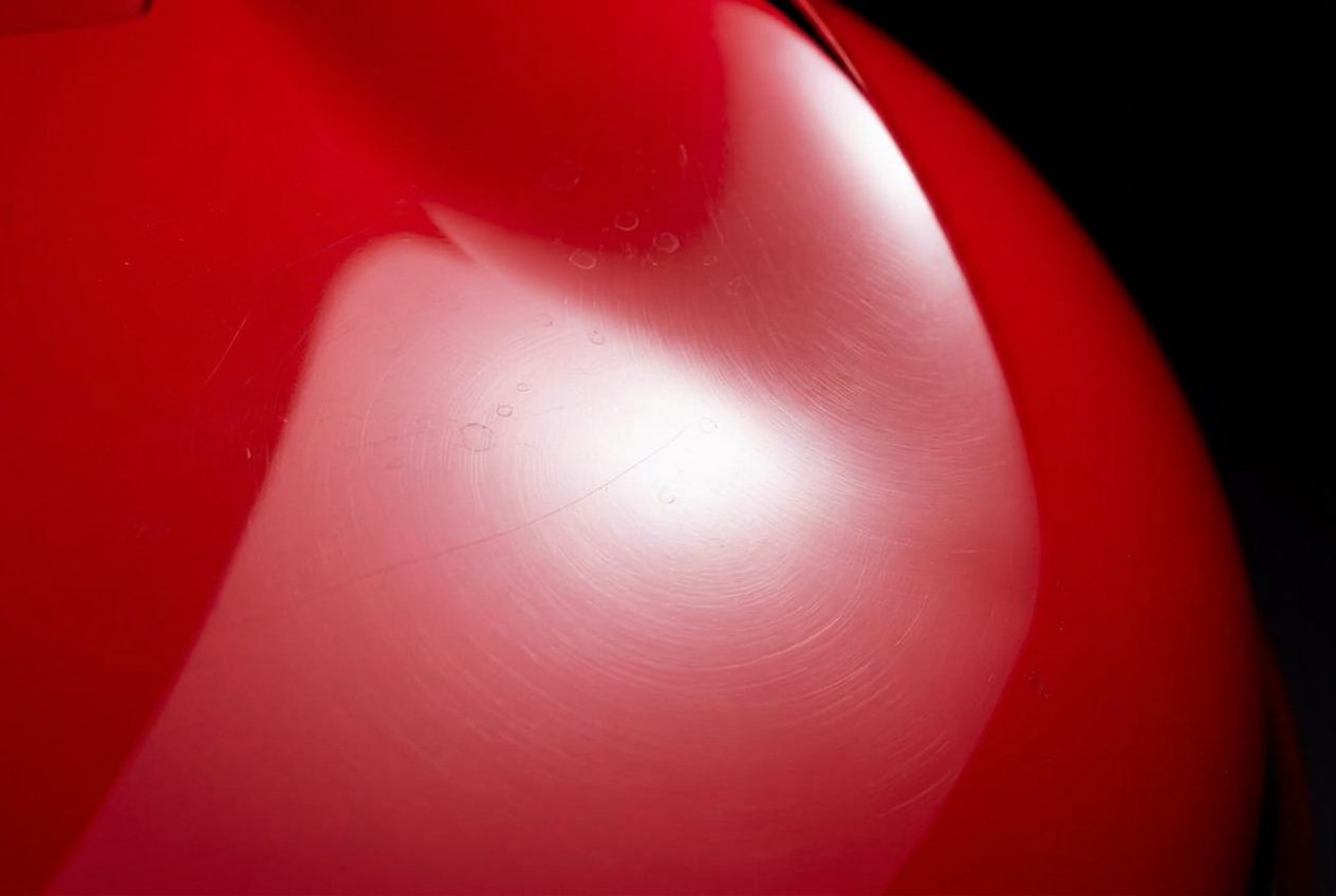 Red Ferrari paint with fine swirl marks and water spots before correction